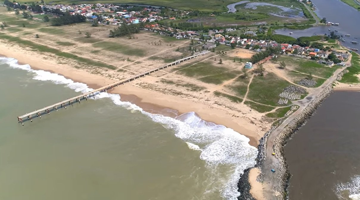 Vista aérea do píer sobre a praia com área urbana ao fundo, Barra do Furado